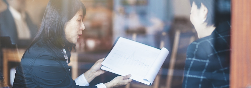 Two senior Japanese business women are talking about business in a cafe.