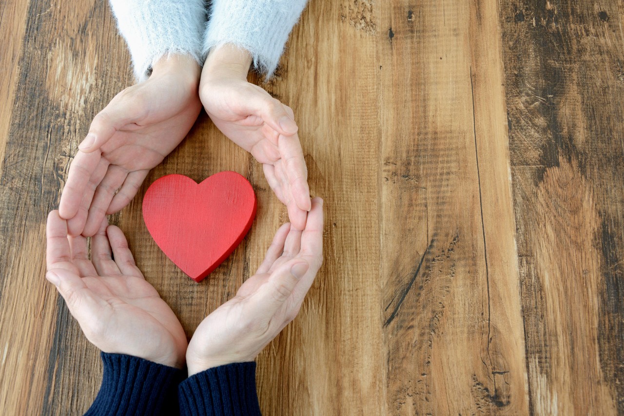 Heart surrounded by man and woman's hand